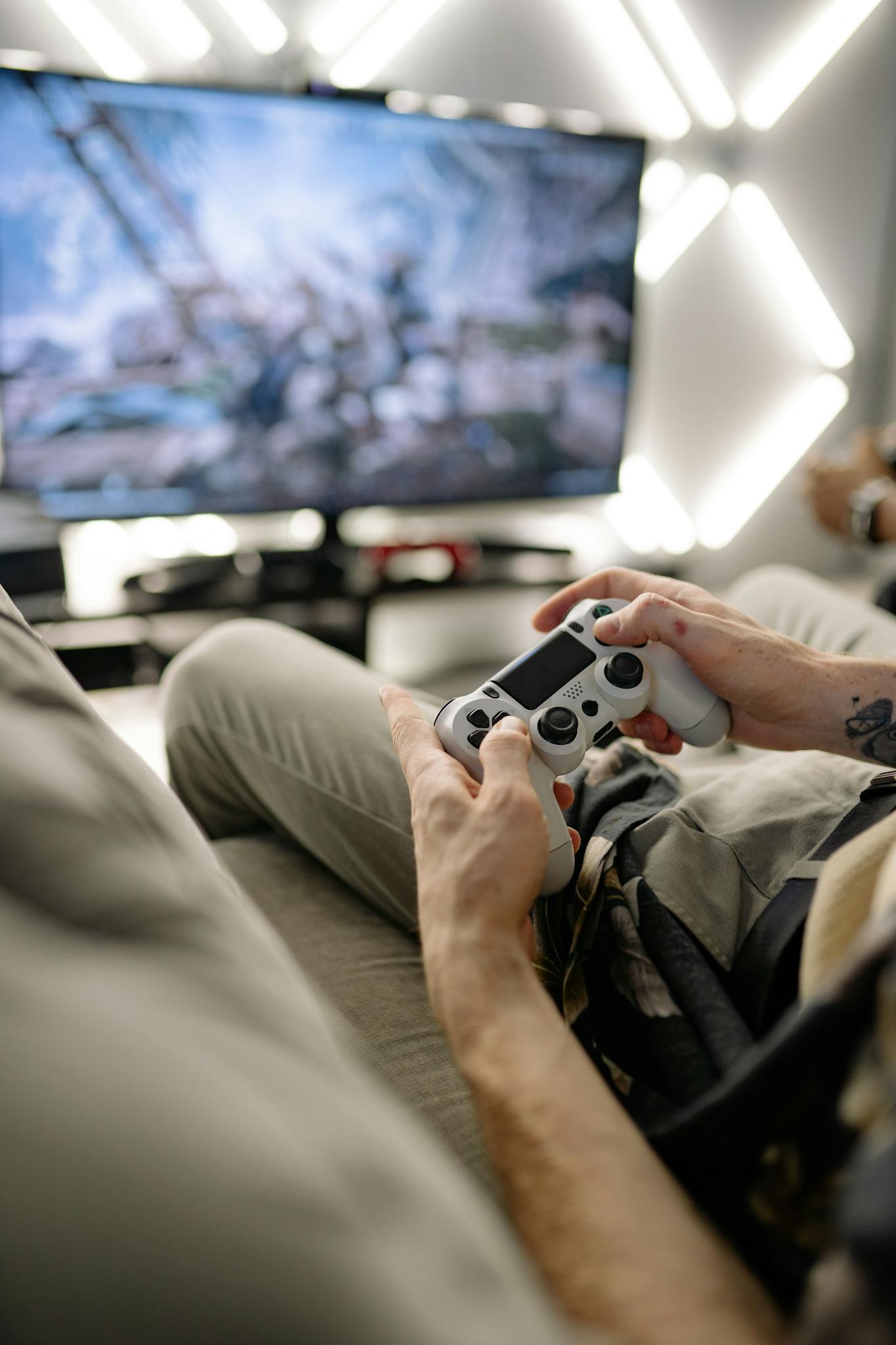 A person holding a game controller playing video games on a sofa indoors.
