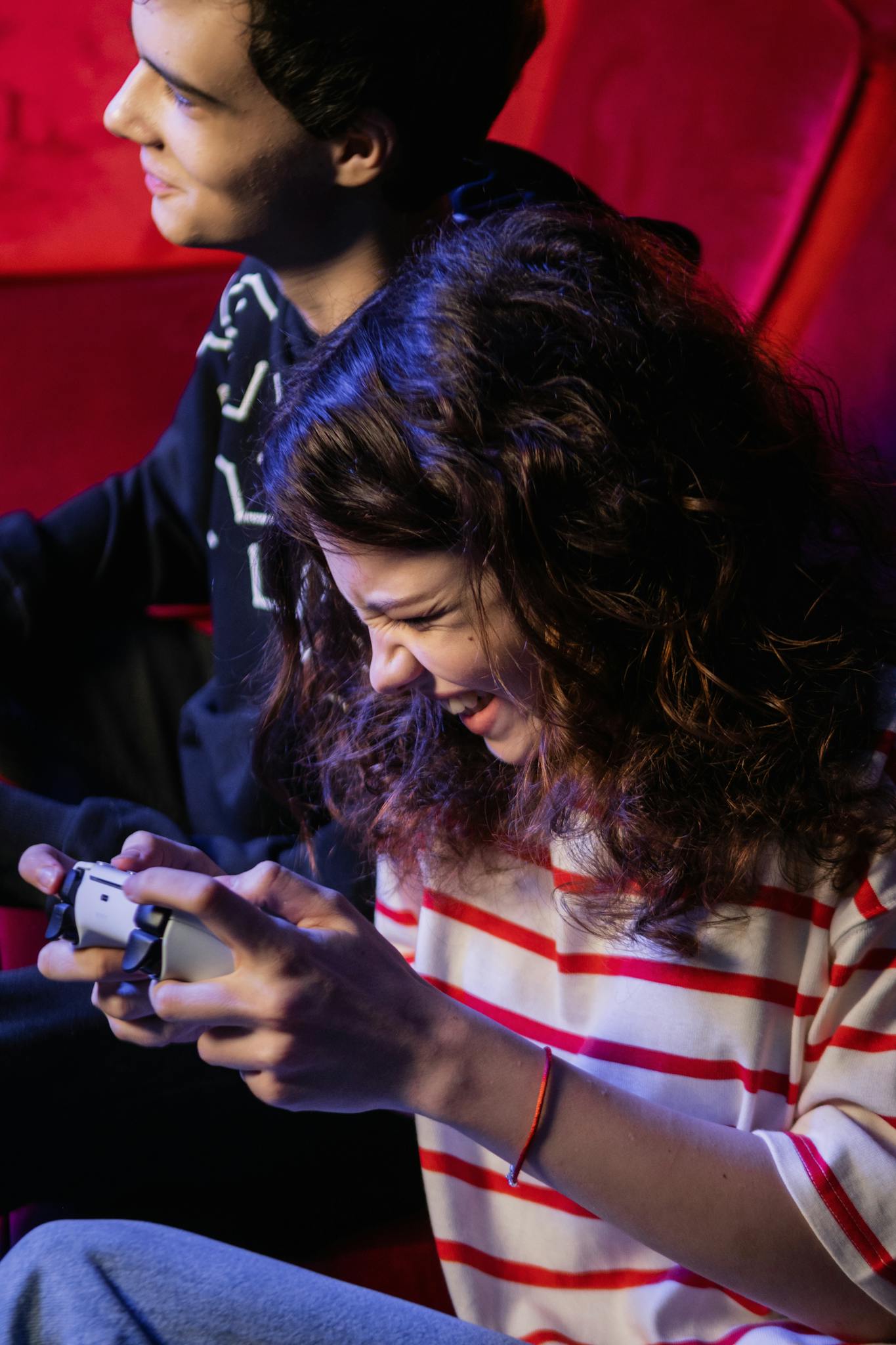 Two teenagers having fun playing a video game indoors, showcasing happy emotions.